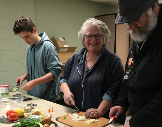 Three individuals posing for photo while cooking