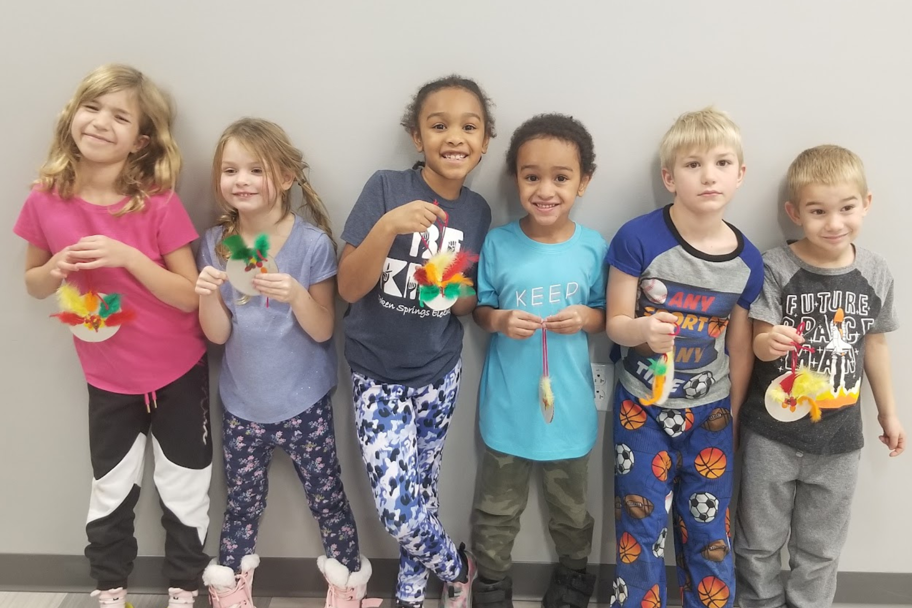 A group of children hold their art projects
